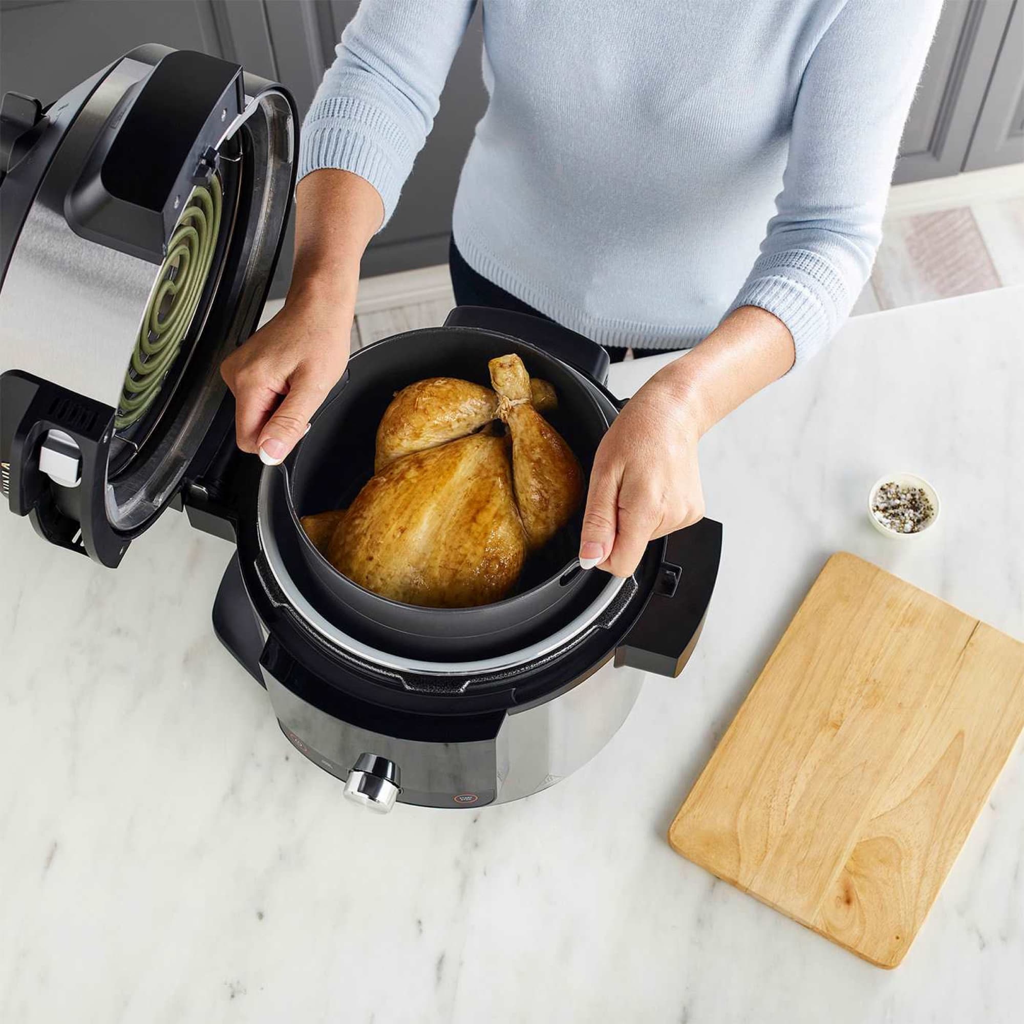A whole chicken being lifted out of the pot