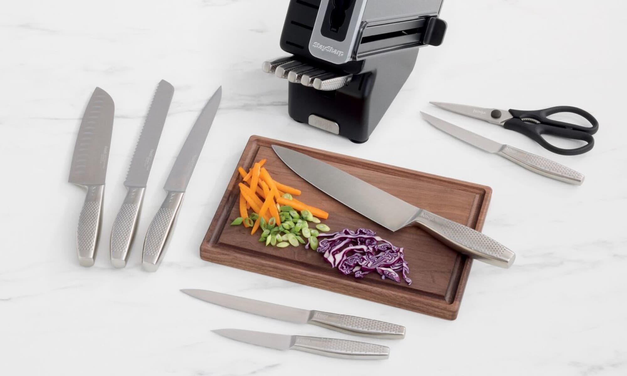 The knives and block next to a board of vegetables