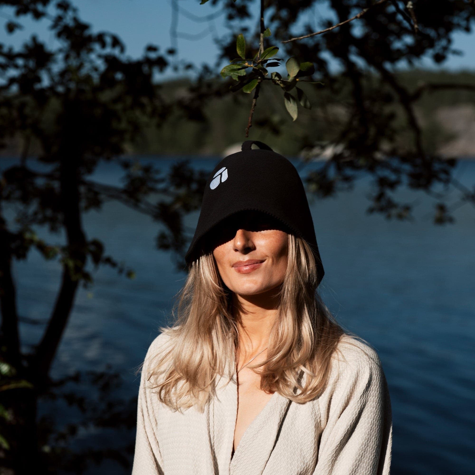 Woman wearing a sauna hat by the water