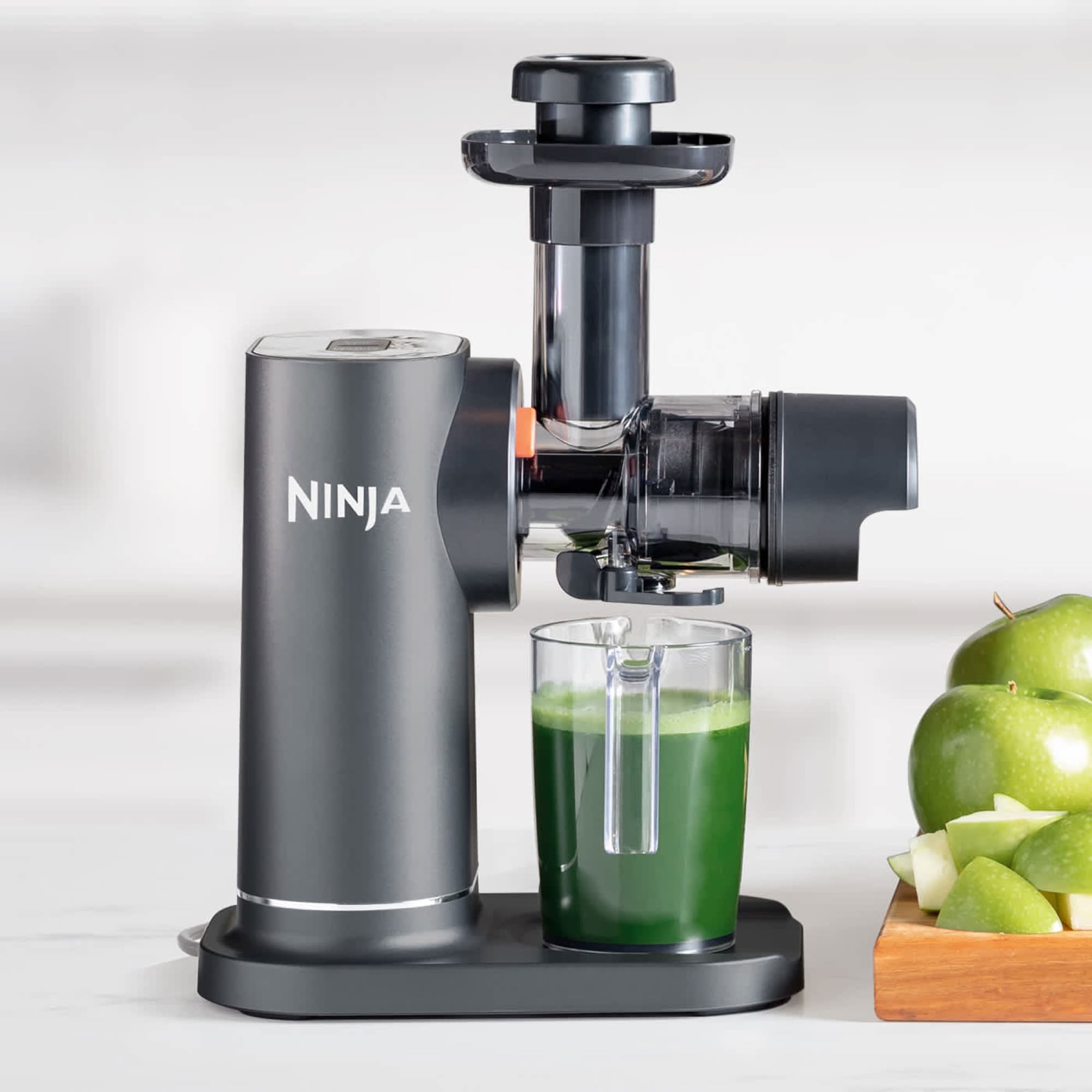 Green juice in the jug next to apples