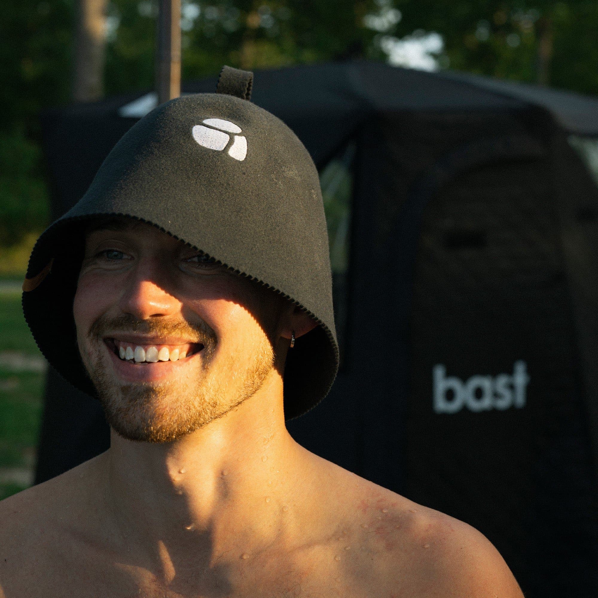 Man wearing a sauna hat in front of a sauna tent