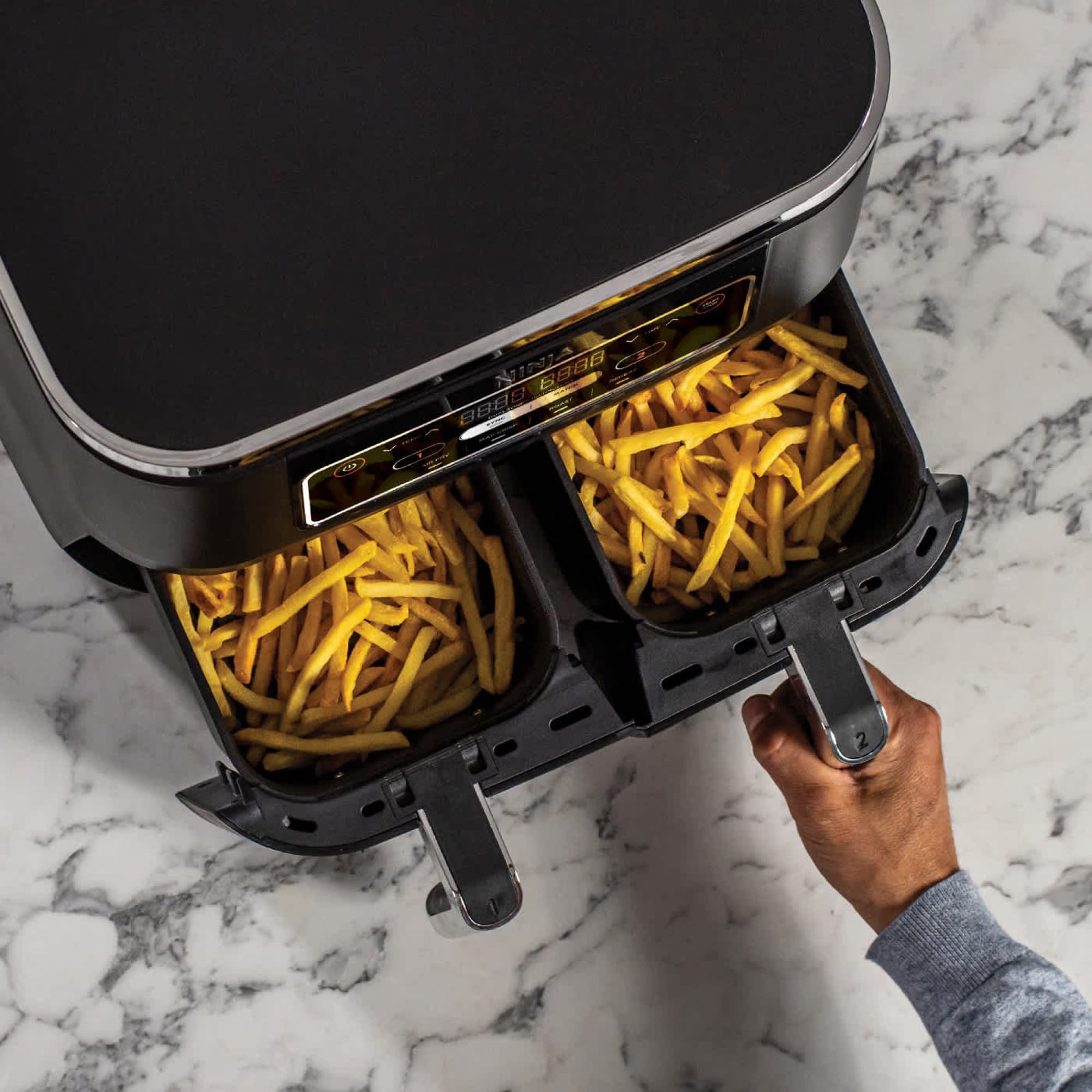 Hand pulling out two drawers of fries