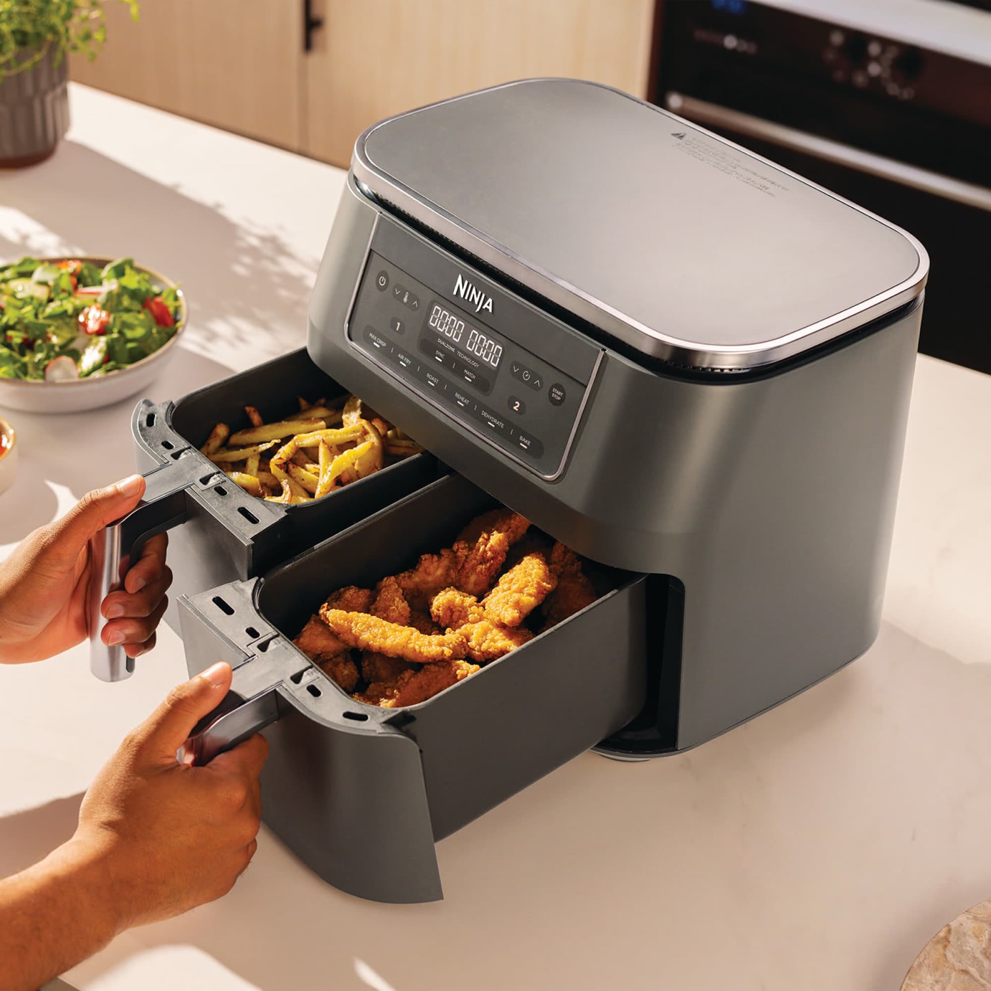 Hands pulling out both drawers with fries and chicken