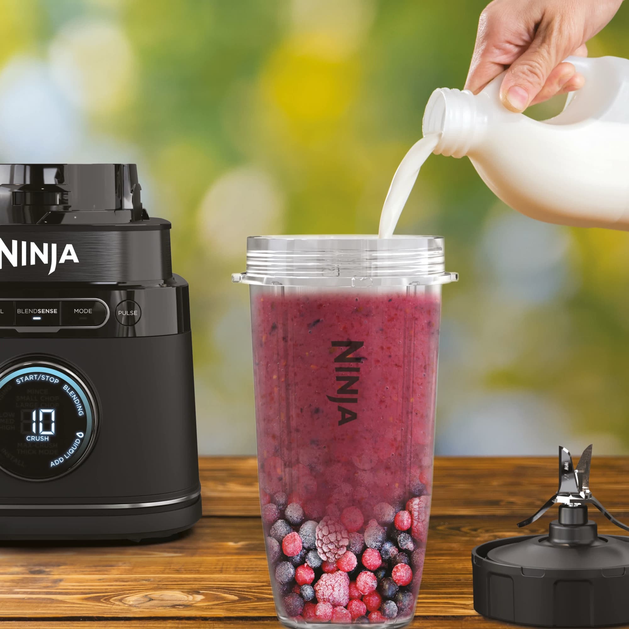 Berry smoothie in a single-serve cup next to the motor