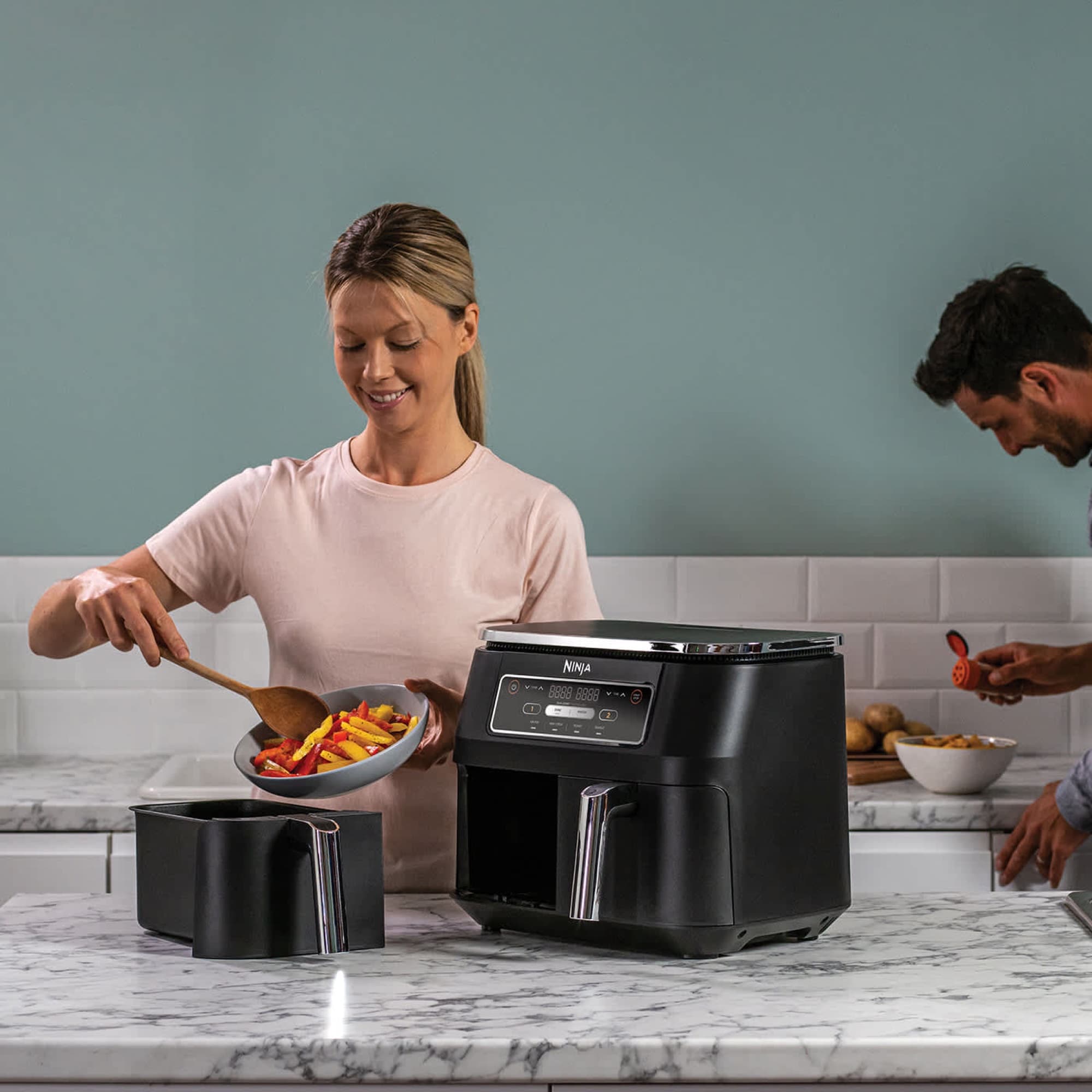 Woman serving vegetables next to the air fryer in the kitchen