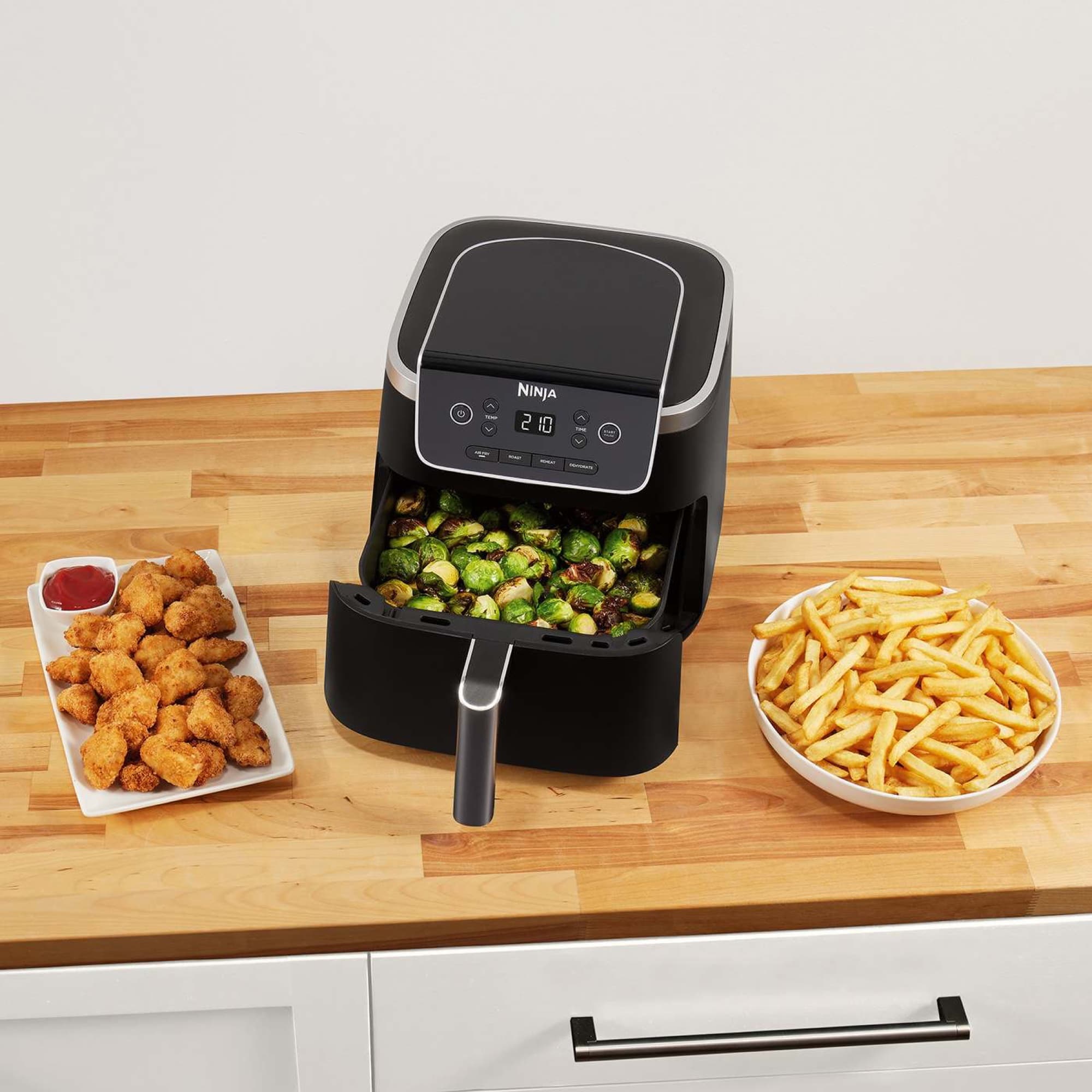 Open drawer with Brussels sprouts, next to plates of fries and chicken