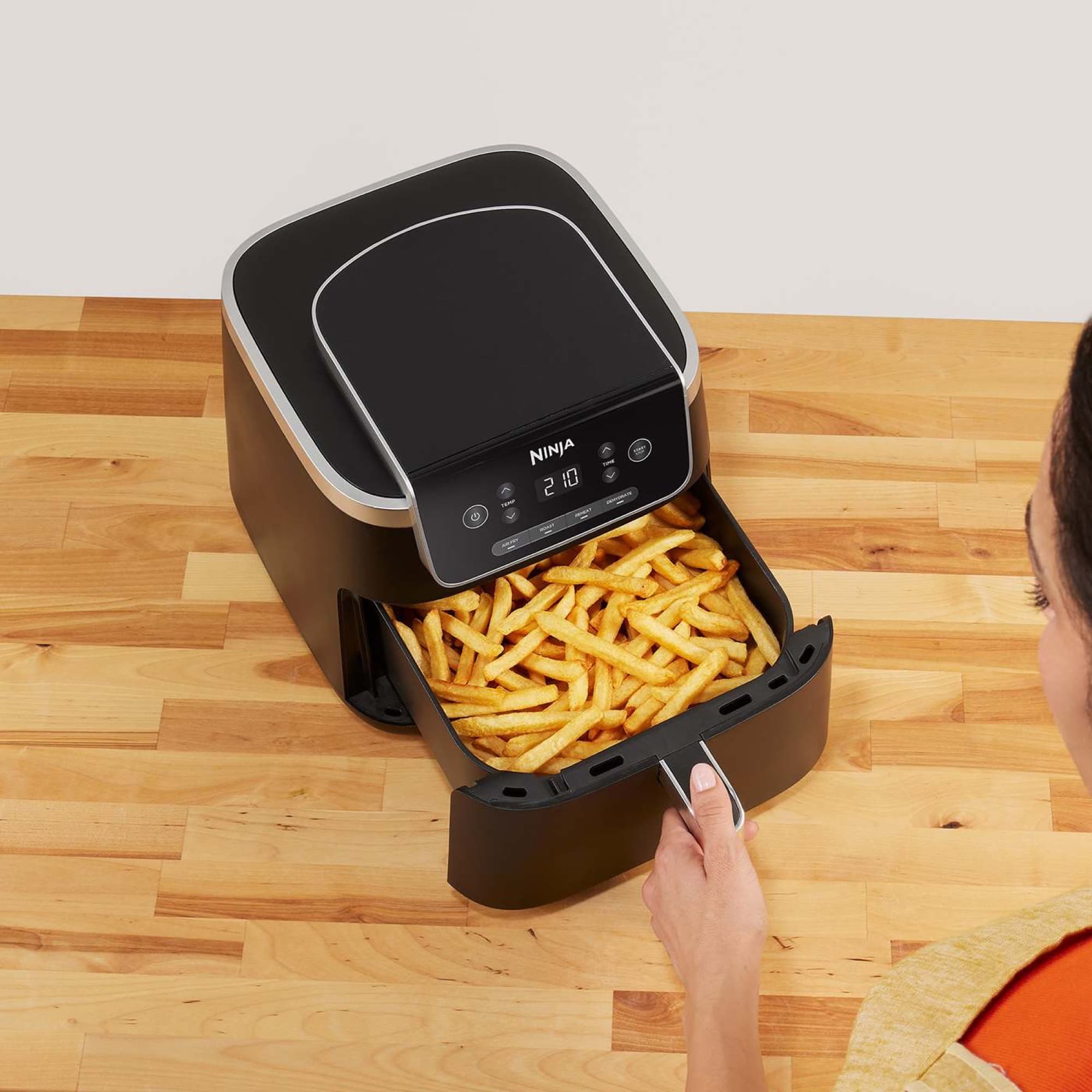 Hand pulling out the drawer full of fries